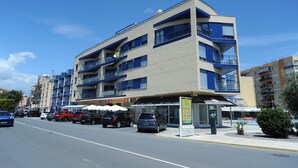 Un hotel de varios pisos con balcones, una zona de estacionamiento y un letrero visible.