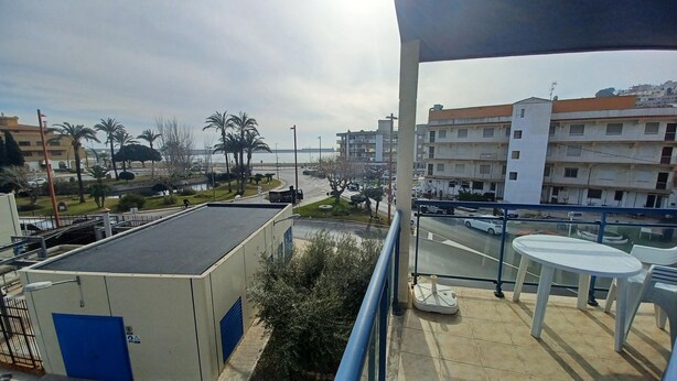 Un balcón con vistas a una zona costera, con edificios y palmeras.
