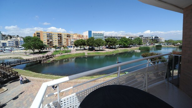 Un balcón con vista a un río, edificios y un parque.