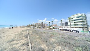 A coastal hotel with multiple floors, a sandy beach in the foreground, and a clear blue sky. - BAIX MAESTRAT (Peñiscola)