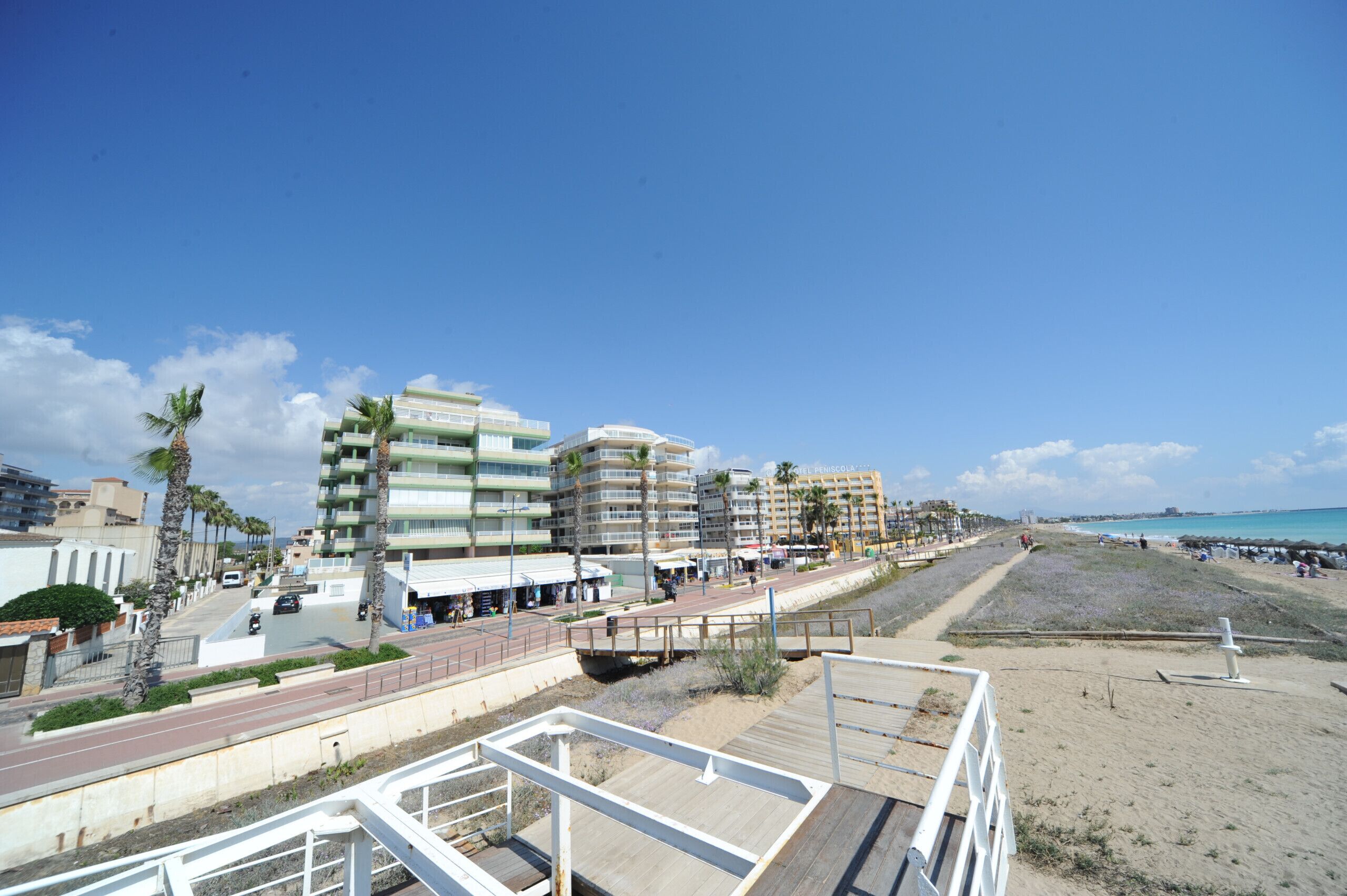 Uma orla costeira com edifícios modernos, praia e calçada para pedestres.