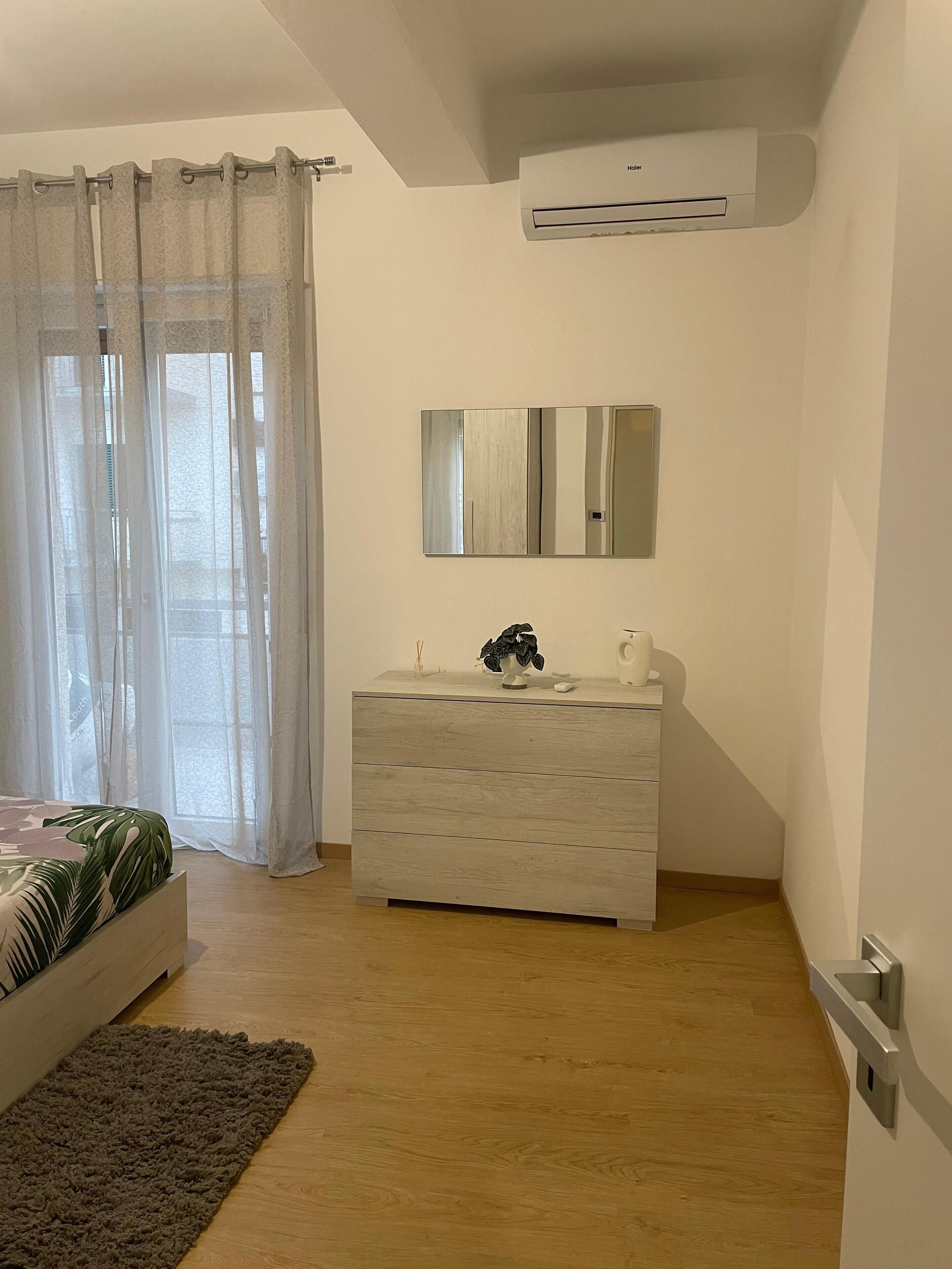 Una camera da letto con un letto, una cassettiera, uno specchio e un condizionatore d'aria.