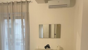A bedroom with a bed, a dresser, a mirror, and an air conditioning unit. - Palmi Bay Home (Palmi)