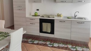 A modern kitchen with white cabinets, a built-in oven, and a sink. - Palmi Bay Home (Palmi)