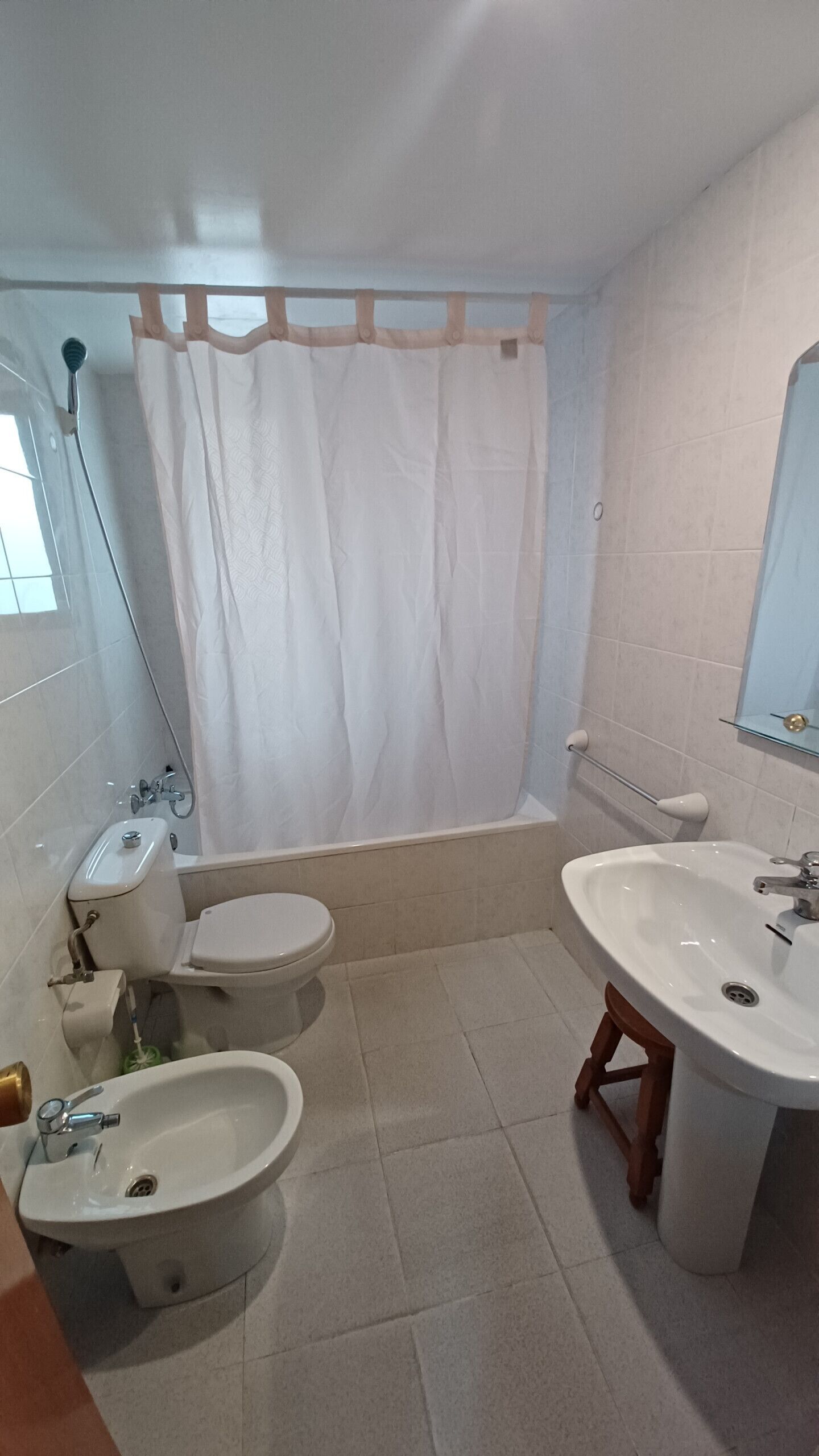 Une salle de bain avec une baignoire, deux toilettes, un bidet, un lavabo et un miroir.