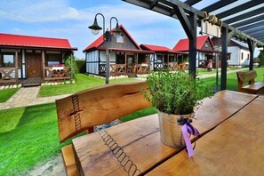 Relax in a charming outdoor seating area with a bench and table, surrounded by lush greenery and traditional buildings.