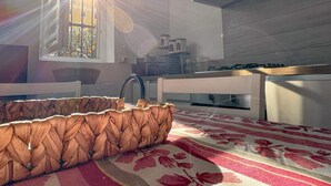 A modern kitchen with a built-in stove, a window with sunlight streaming in, and a patterned rug on the floor. - Appartamento Casa NUNI (Lavagna)