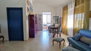 A living room with a blue sofa, a TV, and a dining area with chairs and a table.