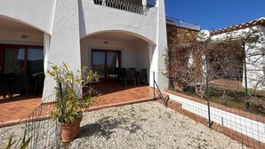 Edifici de dues plantes amb un balcó, una zona de pati amb cadires i un sòl de grava.
