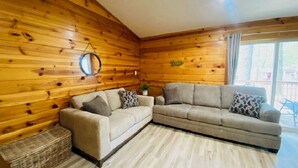Une pièce chaleureuse avec des murs en bois, un canapé beige et un petit miroir rond.