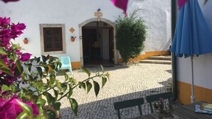 A courtyard with a white building, a blue umbrella, and a bench. - Quinta Laranja - Apartment first floor - "Adega" (Alvorninha)