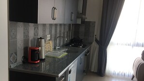 A modern kitchen with dark cabinets, a stainless steel coffee maker, and a dishwasher. - Söğüt Butik Apart (Sögüt)