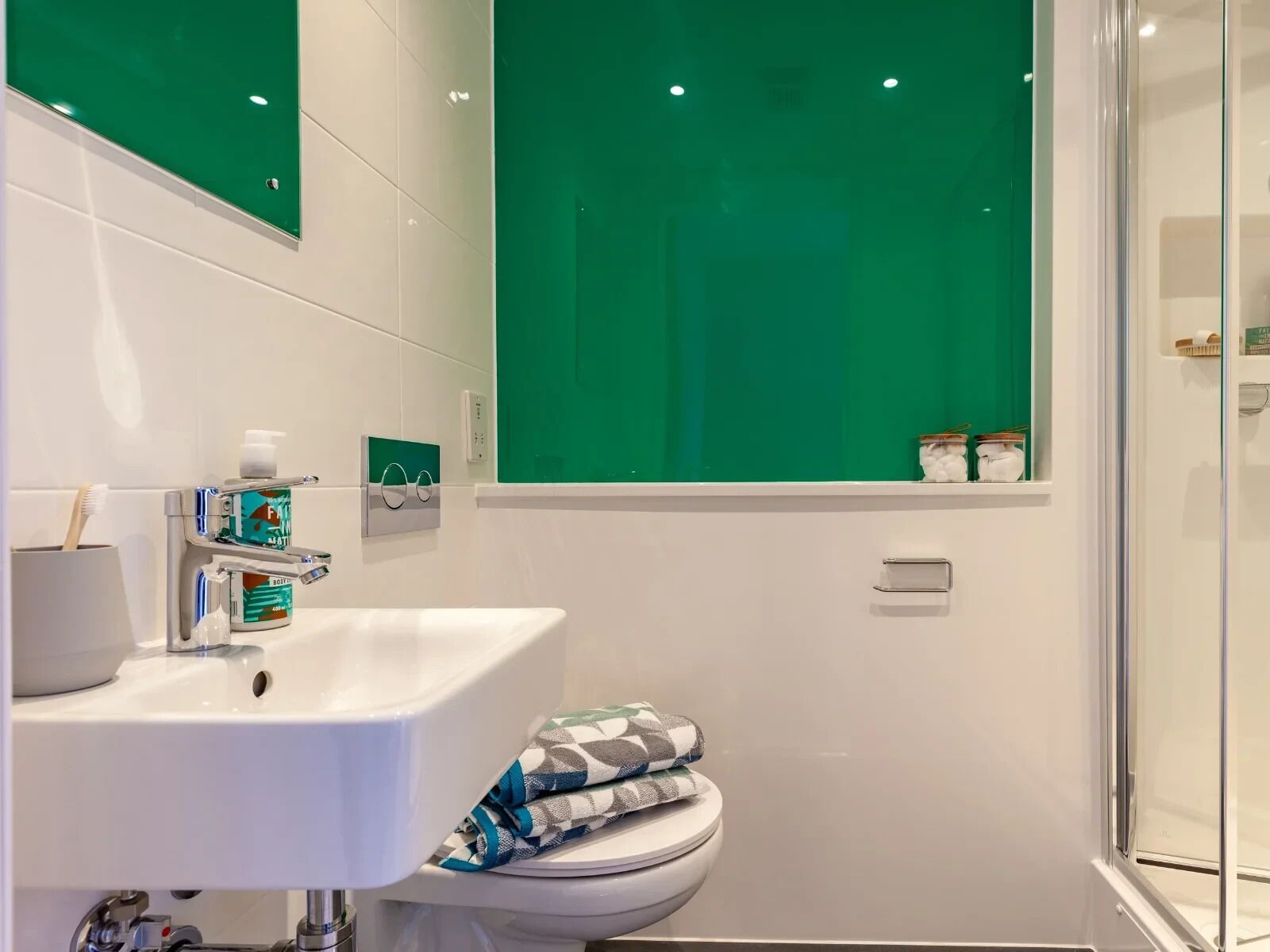 Ein modernes Badezimmer mit einem weißen Waschbecken, einer Toilette und einer Dusche.