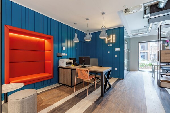 A modern office space with a blue wall, a red accent wall, and a wooden desk with a computer.