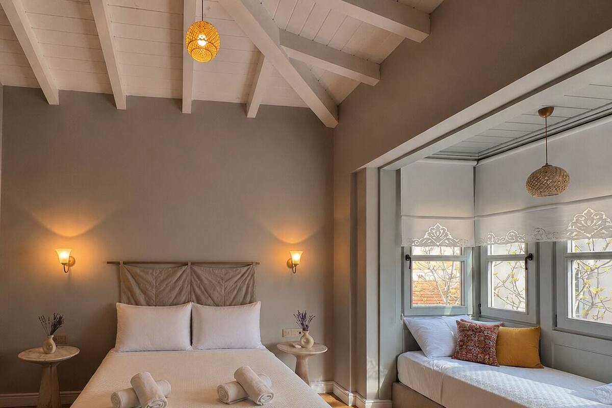 A bedroom with a large bed, two bedside tables, a sofa bed, and a window with a view.