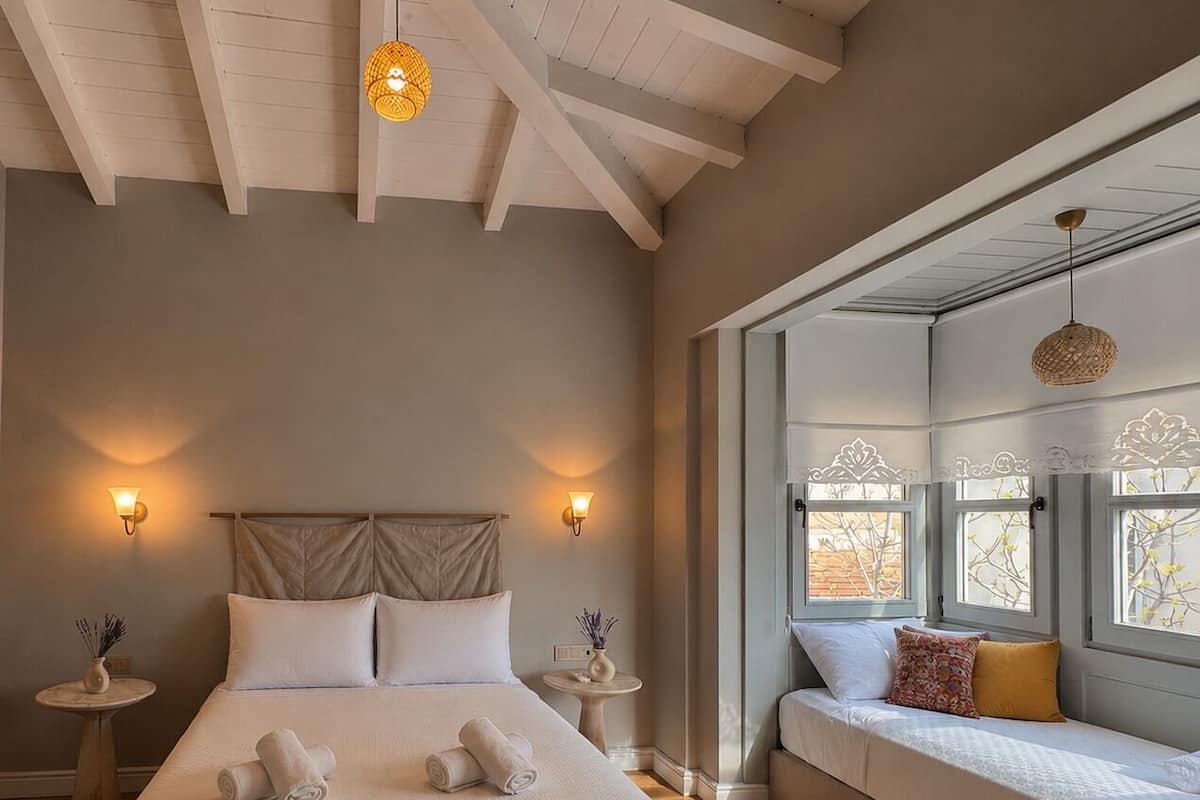 A bedroom with a large bed, two bedside tables, a sofa bed, and a window with a view.