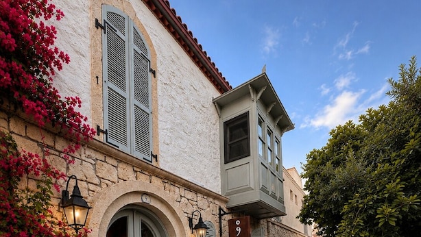 A cobblestone street with a building featuring a stone facade, a balcony, and outdoor seating. - No9 Alacati (Cesme)