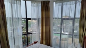 Una camera d'albergo con un letto grande, tende leggere e vista sulla città.