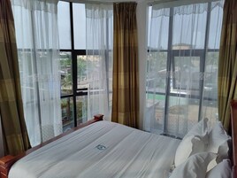 Habitación de hotel con una cama grande, cortinas de gasa y vistas a la ciudad.