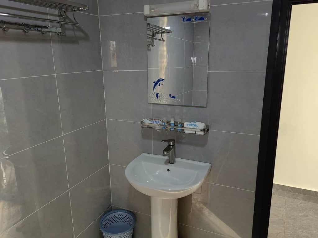 A bathroom with a white sink, a mirror, and a towel rack.