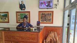 Una reception con un quadro appeso al muro, uno schermo televisivo e una sedia di legno.