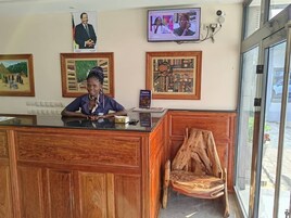 Un mostrador de recepción con obras de arte enmarcadas en la pared, una pantalla de televisión y una silla de madera.