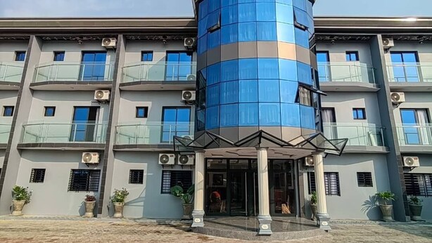 Un hotel a più piani con una torre cilindrica centrale blu, balconi e piante in vaso.