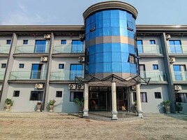Un hotel de varios pisos con una torre central cilíndrica azul, balcones y plantas en macetas.