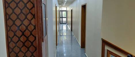 A hallway with a patterned door, a framed picture on the wall, and a view into another room.