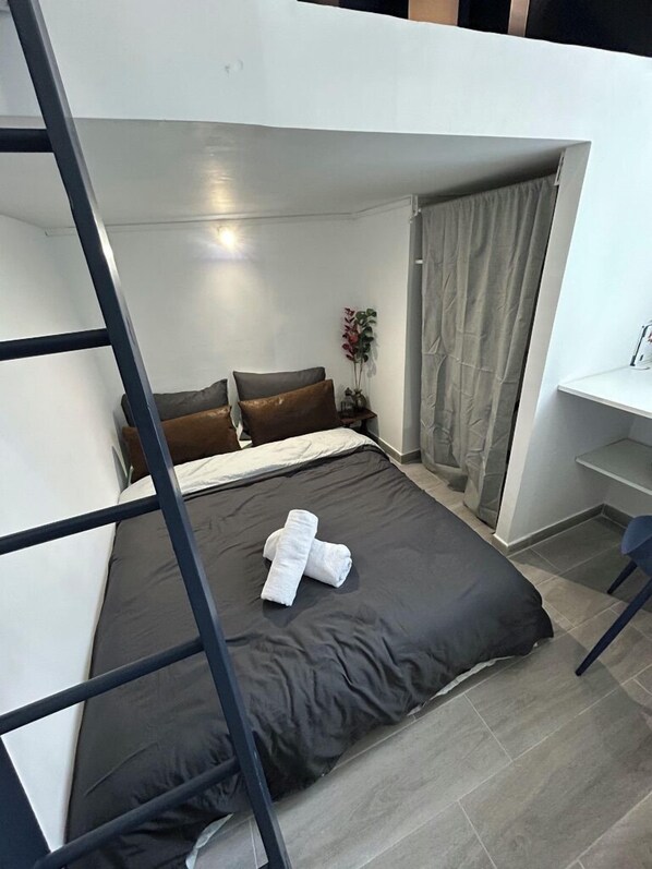 A compact bedroom with a bunk bed, a bedside table, a small desk, and a potted plant. - APPARTEMENT PARIS CDG COSY ET LUMINEUX (Livry-Gargan)