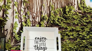 A room with a wall decorated with artificial vines and a sign that reads "enjoy the little things." There are two wooden boxes with items inside, and a small table with a lamp. - APPARTEMENT PARIS CDG COSY ET LUMINEUX (Livry-Gargan)