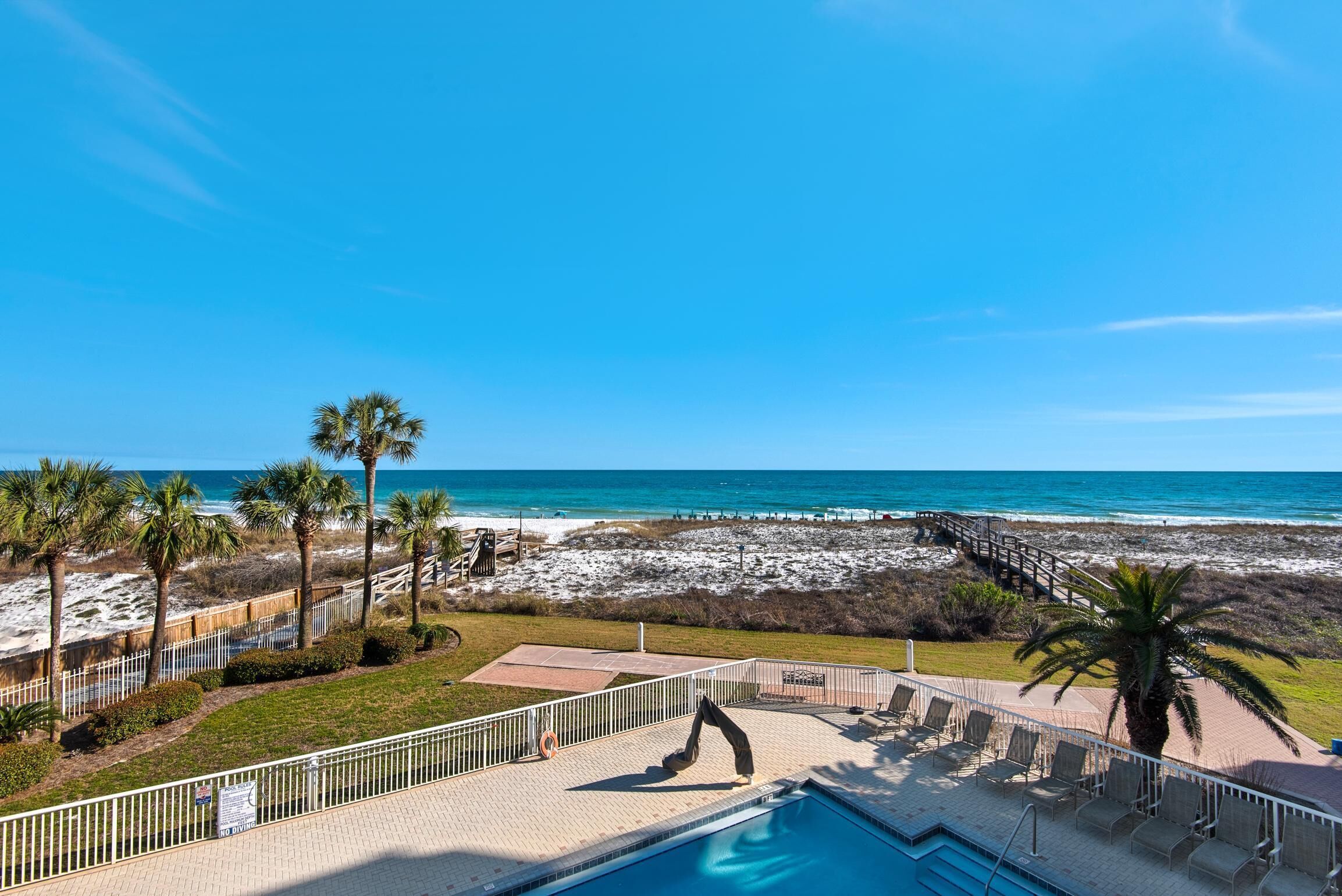 A pool area with a view of the beach and ocean.