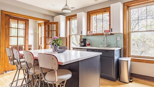 A modern kitchen with a central island, bar stools, a coffee machine, and a trash can. - 15min Drive to Med District.20min Dr to Fulton Mkt. Direct Bus to Union Station. (Chicago)
