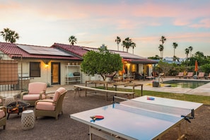 Une terrasse avec une table de ping-pong, des sièges d’extérieur et une piscine.