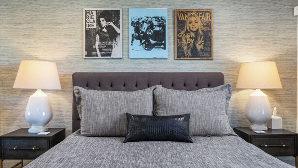 Una camera da letto con un letto, due comodini, due lampade, una testiera e tre poster appesi al muro.