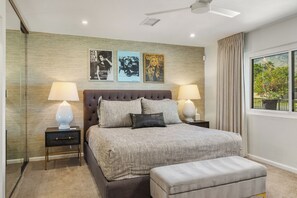 Ein Schlafzimmer mit einem großen Bett, zwei Nachttischen mit Lampen, einem Deckenventilator und drei gerahmten Postern an der Wand.