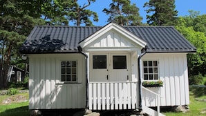 A small, single-story cabin with a gabled roof, white exterior walls, and a front porch with a white picket fence. - Holiday Home, 250m From sea (Stenungsund)
