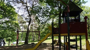 A playground with a yellow slide, red and yellow climbing structures, and a small shelter. - Holiday Home, 250m From sea (Stenungsund)