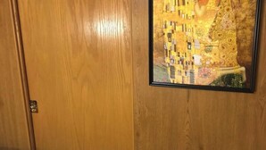 A room with a wooden wardrobe, a framed painting of a woman in a yellow dress, and a bed with a patterned bedspread. - Gustav Klimt The Kiss -Camper/RV in Saint Matthews, South Carolina (Saint Matthews)