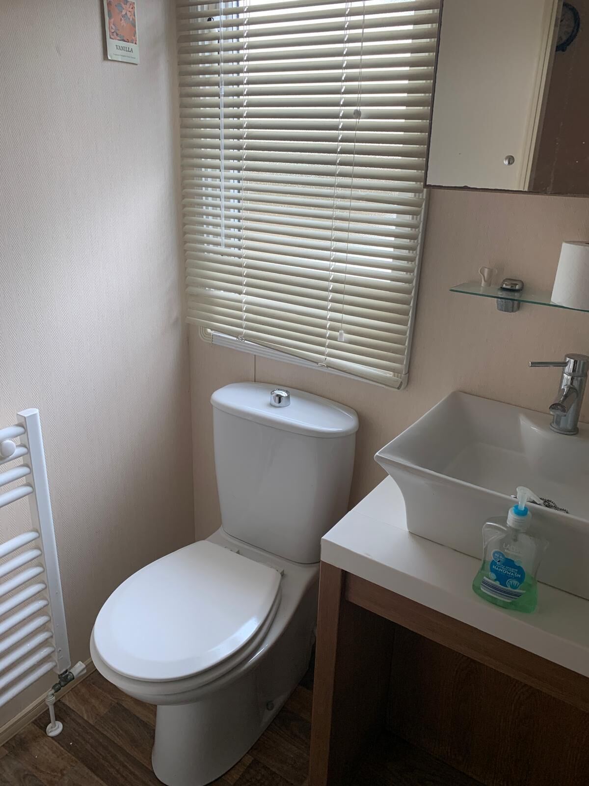 A small bathroom with a toilet, a sink, and a window with blinds.