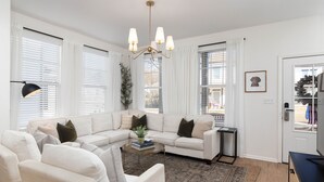 A modern living room with a sectional sofa, a coffee table, and a chandelier. - Colonel's Cottage Oxford - 2mi to The Square (Oxford)