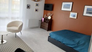 A modern bedroom with a bed, a chair, a dresser, and a radiator.