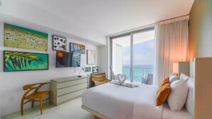 A hotel room with a large bed, a desk, and a view of the sea. - Enjoy a luxurious apartment on the beach! (Hollywood)