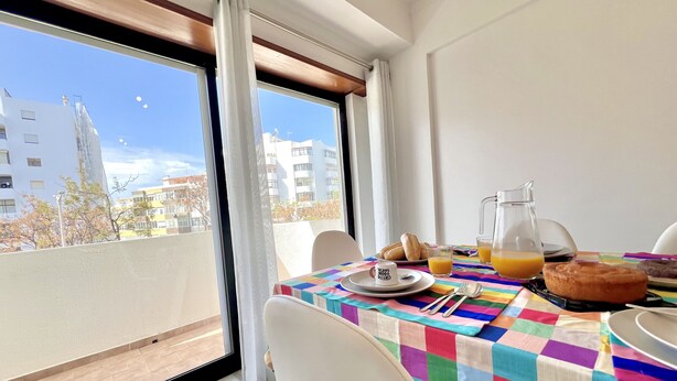 Un balcón con una mesa dispuesta para el desayuno, con croissants, jugo y un muffin.