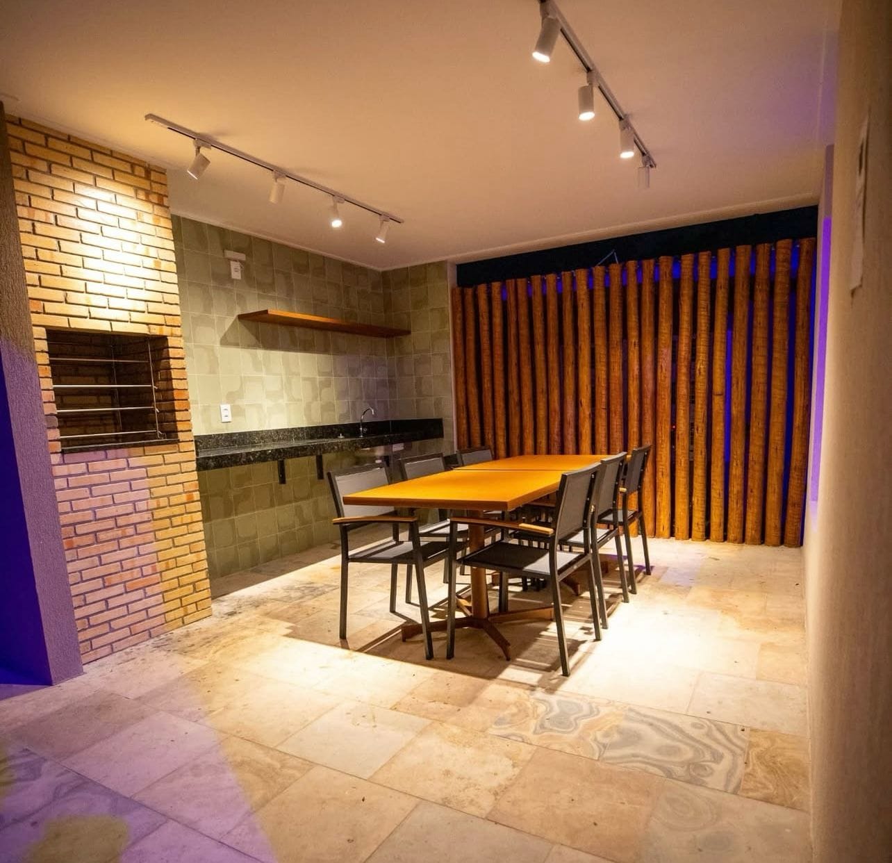 Un comedor con pared de ladrillo, una mesa de madera y sillas.