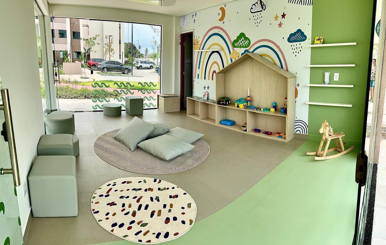 A children's playroom with a green wall, a wooden playhouse, and a large window.