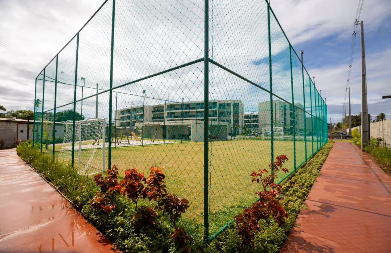 Un campo deportivo rodeado por una cerca verde de malla bajo un cielo despejado.