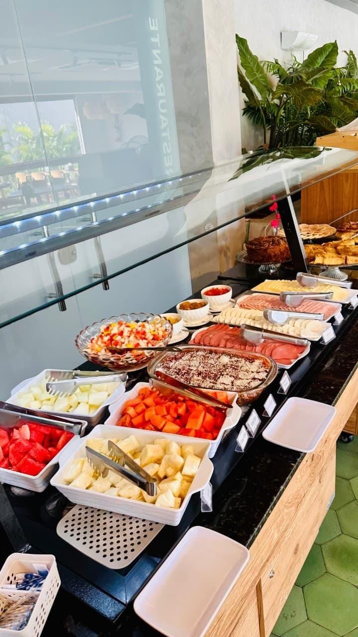 En buffet med et udvalg af mad, herunder frugt, kød og desserter, anrettet på en disk med en glasmontre.