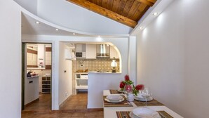A modern kitchen with white cabinets, a microwave, and a dining area with a table set for two. - Villa Piccola Stella with attached annex and private pool (Sardegna)