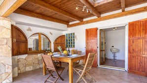 A rustic dining area with a wooden table, stone walls, and wooden doors. - Villa Piccola Stella with attached annex and private pool (Sardegna)